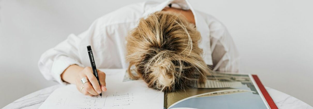 Woman behind a work desk exhibiting symptoms of work related burnout