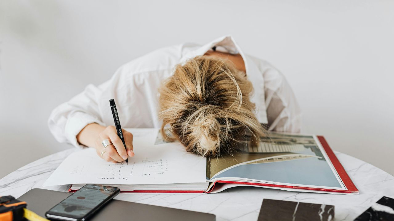 Woman behind a work desk exhibiting symptoms of work related burnout